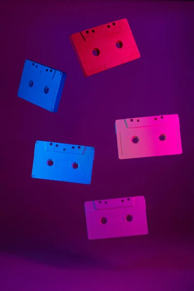Farbige Audiokassetten hängen vor violettem Hintergrund in der Luft — Stockfoto