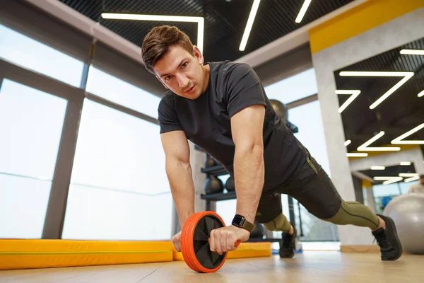 Sportovní sportovec dělá cvičení s abs kolečko v tělocvičně — Stock fotografie