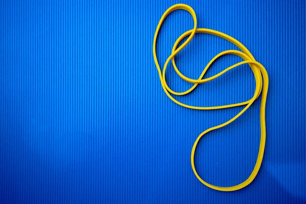 Yellow fitness rope on blue mat background — Stock Photo, Image