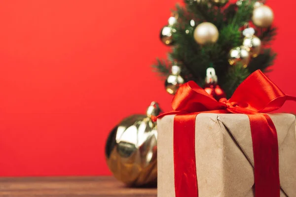 Presente de Natal embrulhado em papel artesanal com fita vermelha em um fundo festivo vermelho — Fotografia de Stock