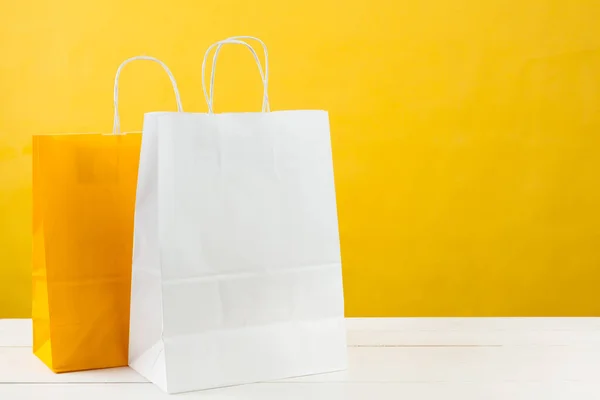 Sacos de compras de papel no fundo amarelo brilhante — Fotografia de Stock