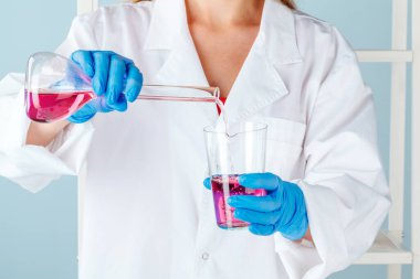 Kimyager eller sıvı ile test tüpleri tutarak ve deneyler yapıyor