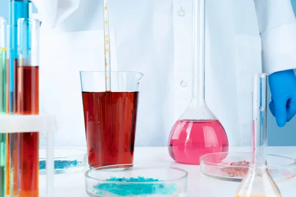 Manipolazioni con contenitori chimici in vetro da laboratorio in tavola — Foto Stock