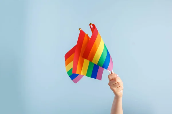 Гей прапори в жіночій руці на сірому фоні — стокове фото