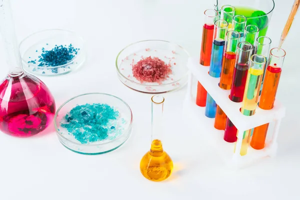 Χρωματιστά υγρά μέσα σε γυάλινα εργαστήρια σε λευκό τραπέζι στο εργαστήριο — Φωτογραφία Αρχείου