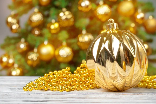 Christmas baubles on wooden table against decorated christmas tree blurred background — Stock Photo, Image