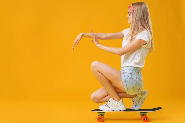 Досить щаслива жінка випадково одягнена сидить на скейтборді — стокове фото