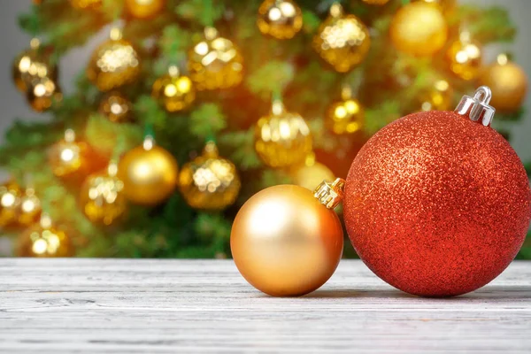 Kerstballen op houten tafel tegen versierde kerstboom onscherpe achtergrond — Stockfoto