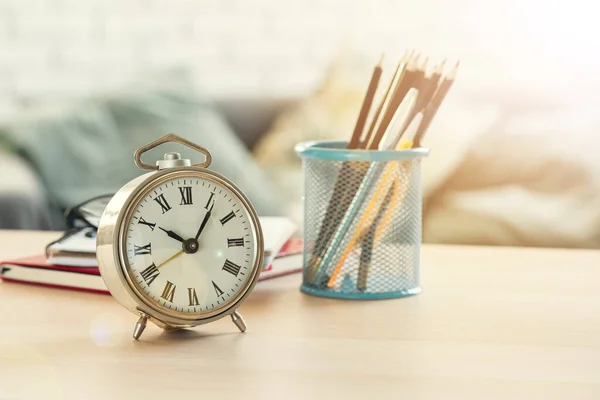 Relógio de alarme e objetos de papelaria de escritório fechar em cima da mesa de madeira — Fotografia de Stock