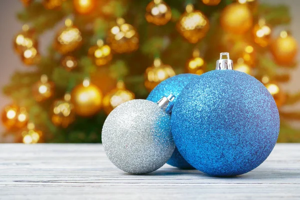 Julgranskulor på träbord mot dekorerade julgran suddig bakgrund — Stockfoto