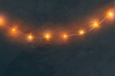 Ilık ışıklandırılmış çelenk koyu arkaplanı kapatır