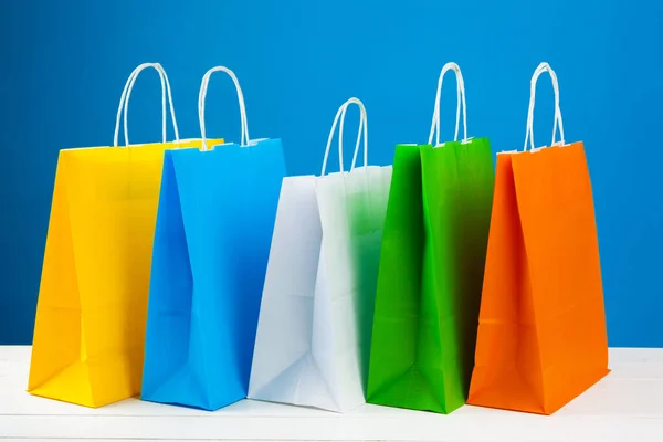 Arranjo de sacos de compras em fundo azul — Fotografia de Stock