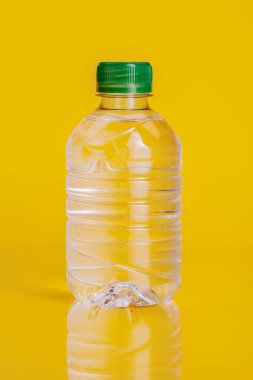 Parlak sarı arka plan üzerinde maden suyu Plastik şişe