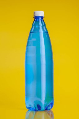 Parlak sarı arka planda içki dolu plastik şişe