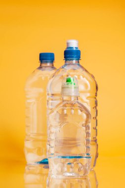 Parlak sarı arka plan üzerinde maden suyu Plastik şişe