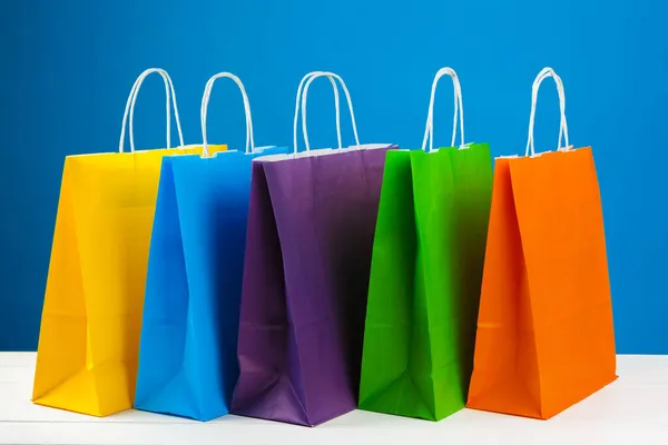 Arranjo de sacos de compras em fundo azul — Fotografia de Stock
