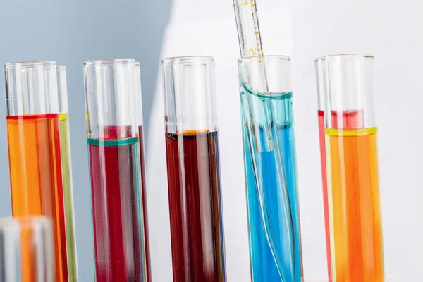 Mãos de químicos segurando tubos de ensaio com líquidos e fazendo experimentos — Fotografia de Stock
