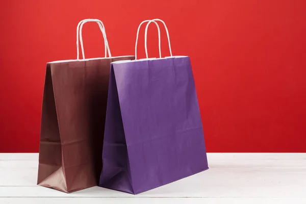 Sacos de compras de papel com espaço de cópia no fundo vermelho — Fotografia de Stock