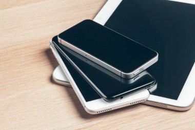 Dijital tablet ve cep telefonu. Ahşap masa üzerinde elektronik cihazlar, yakın çekim.