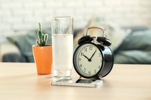 Conceito de saúde da água potável. Relógio despertador e vidro de água na mesa — Fotografia de Stock