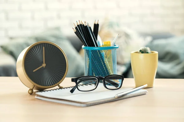 Relógio de alarme e objetos de papelaria de escritório fechar em cima da mesa de madeira — Fotografia de Stock