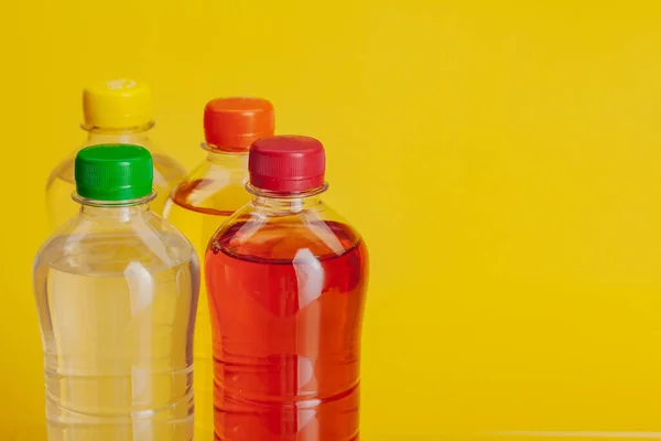 Garrafa de plástico cheia de bebida em um fundo amarelo brilhante — Fotografia de Stock