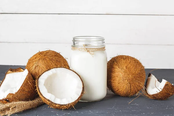 Noix de coco et verre de lait de coco sur fond bois — Photo