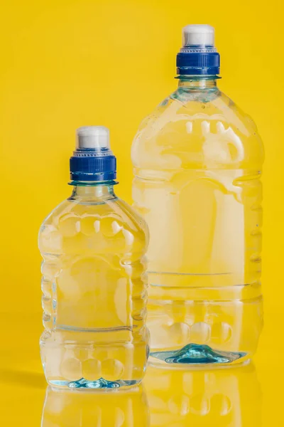 Agua pura en botella de plástico sobre fondo amarillo brillante — Foto de Stock