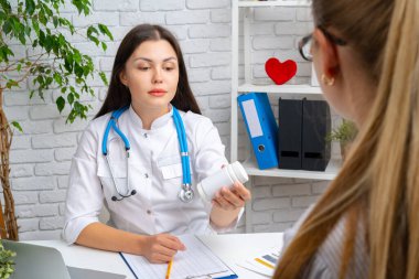 Kadın doktor hastanedeki hastasına reçete yazıyor.