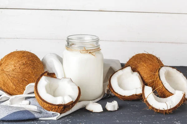 Noix de coco et verre de lait de coco sur fond bois — Photo