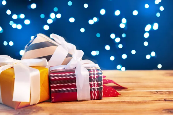Piccole scatole regalo di Natale su tavolo di legno contro bokeh luci sfondo — Foto Stock