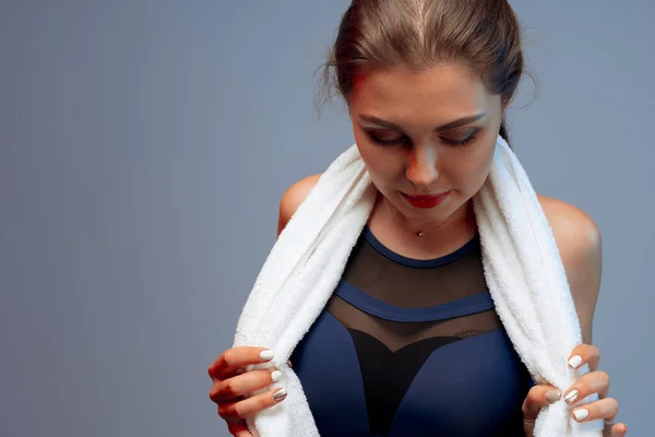 Ωραία νεαρή γυναίκα με αθλητικά ρούχα κρατώντας μια πετσέτα στο γυμναστήριο — Φωτογραφία Αρχείου