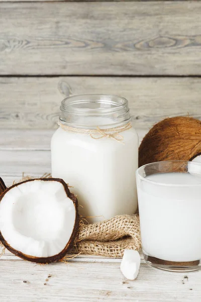 Cocos e jarro de vidro com leite de coco — Fotografia de Stock