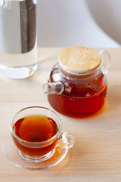 Чайник из стекла с черным чаем на деревянном столе — стоковое фото