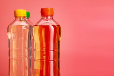 Parlak pembe bir arka plan üzerinde renkli içecek veya limonata şişesi yakın