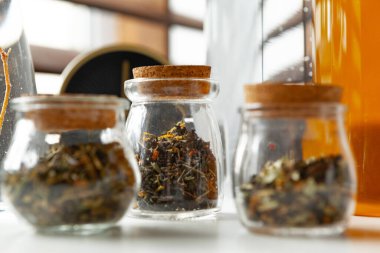 Kuru çay yapraklı cam kavanozlar beyaz masaya yakın.