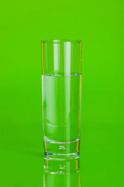 Γυάλινο φλιτζάνι μεταλλικό νερό σε πράσινο φόντο — Φωτογραφία Αρχείου