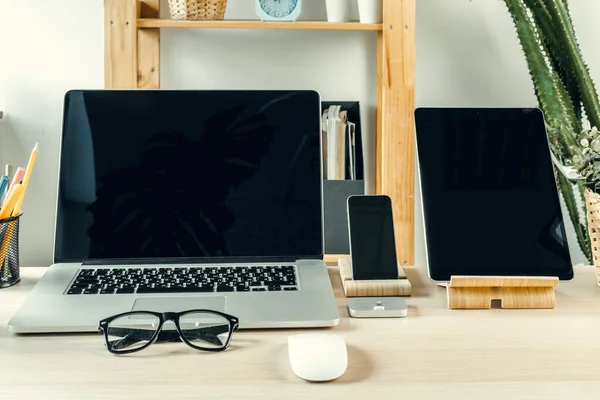 Laptop i ett ljust rum på arbetsbord med kontorsmaterial — Stockfoto