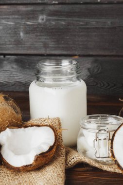 Siyah ahşap arka plan üzerinde kırık hindistan cevizi ve hindistan cevizi sütü