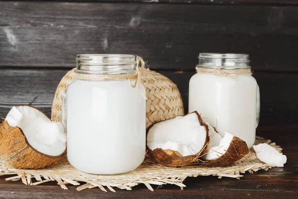 Cocos e jarro de vidro com leite de coco — Fotografia de Stock