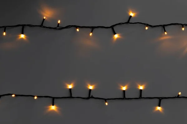 Glowing golden electric garland on a gray background — Stock Photo, Image
