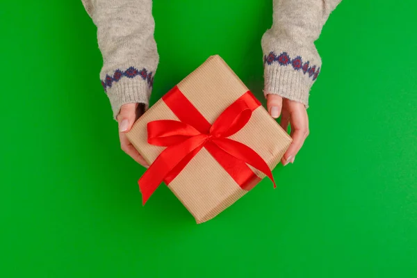 Femme mains tenant boîte cadeau sur fond vert — Photo