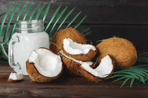 Leche de coco y coco rotos sobre fondo de madera negra —  Fotos de Stock