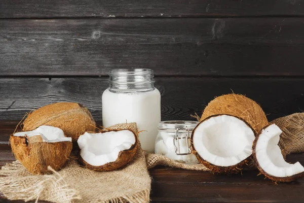 Lait de coco cassé et lait de coco sur fond de bois noir — Photo