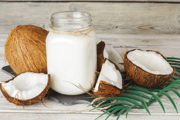 Leite de coco e coco sobre mesa de madeira rústica — Fotografia de Stock