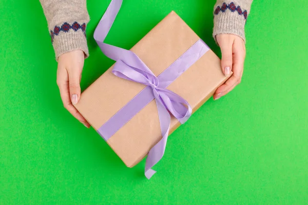 Manos de mujer sosteniendo caja de regalo sobre fondo verde — Foto de Stock