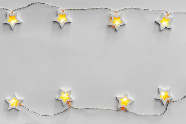 明るい灰色の背景に輝く星型のガーランド — ストック写真