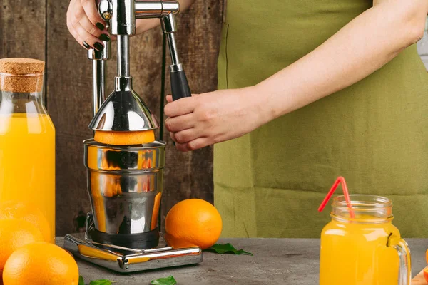 Woman using orange juicer apparatus at home — Stock Photo, Image