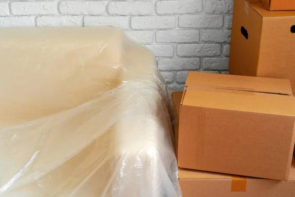 Упакований диван і стопка картонних коробок у кімнаті. Переміщення концепції — стокове фото