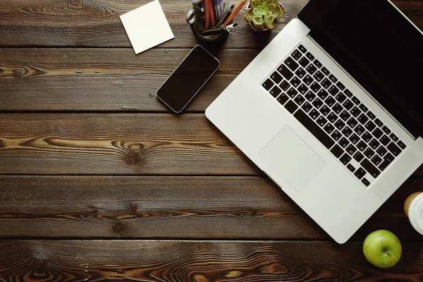 Office desk with laptop computer, supplies and green apple, top view — Stock Photo, Image